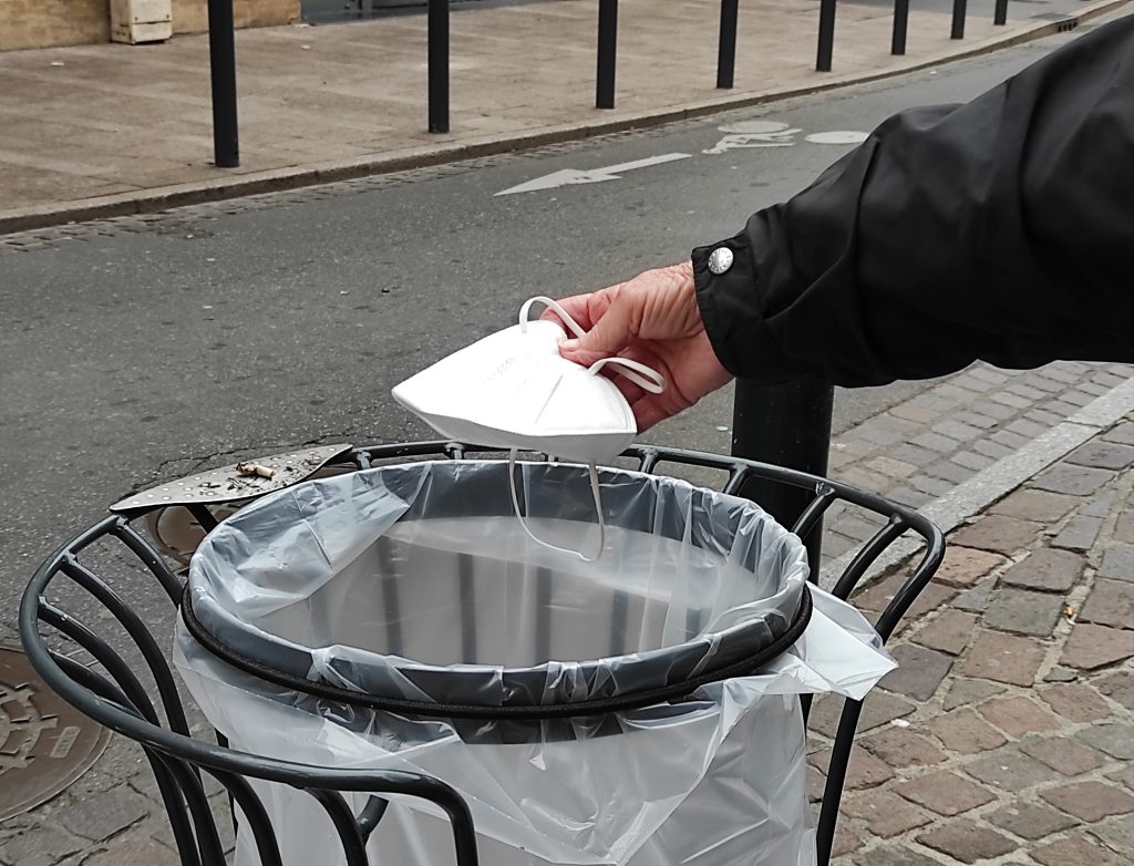Une personne jette son masque chirurgical à la poubelle dans les rues de Toulouse. 